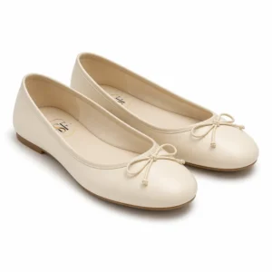 Private label round toe bow ballet flat in an ivory studio presentation, shown from a front three-quarter view for brands, wholesalers, retailers, importers and B2B footwear sourcing.
