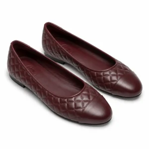 Private label quilted cap toe ballet flat in a burgundy studio presentation, shown from a front three-quarter view for brands, wholesalers, retailers, importers and B2B footwear sourcing.